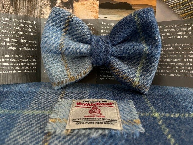 May include: A blue tweed bow tie with a matching fabric square. The bow tie is made of a textured fabric with a plaid pattern. A label on the fabric square reads "Harris Tweed Outer Hebrides of Scotland 100% Pure New Wool."