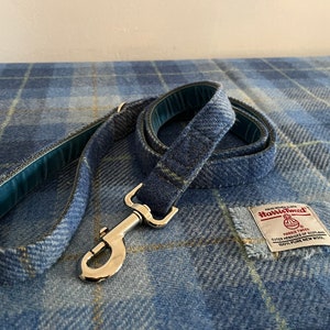 May include: A blue plaid dog leash with a silver metal clasp and a matching blue plaid fabric. The leash has a teal lining and a Harris Tweed label.