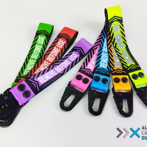 May include: Six colorful keychains with black metal clips and the text "Remove Before Use" printed on them. The keychains are in the colors green, red, purple, blue, orange, and yellow.