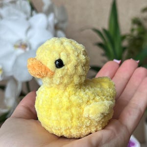 Puede incluir: Un peque&ntilde;o patito amarillo hecho a mano, con pico naranja y ojos negros. El peluche est&aacute; hecho de un material suave y texturizado. El pato es un art&iacute;culo encantador y artesanal.