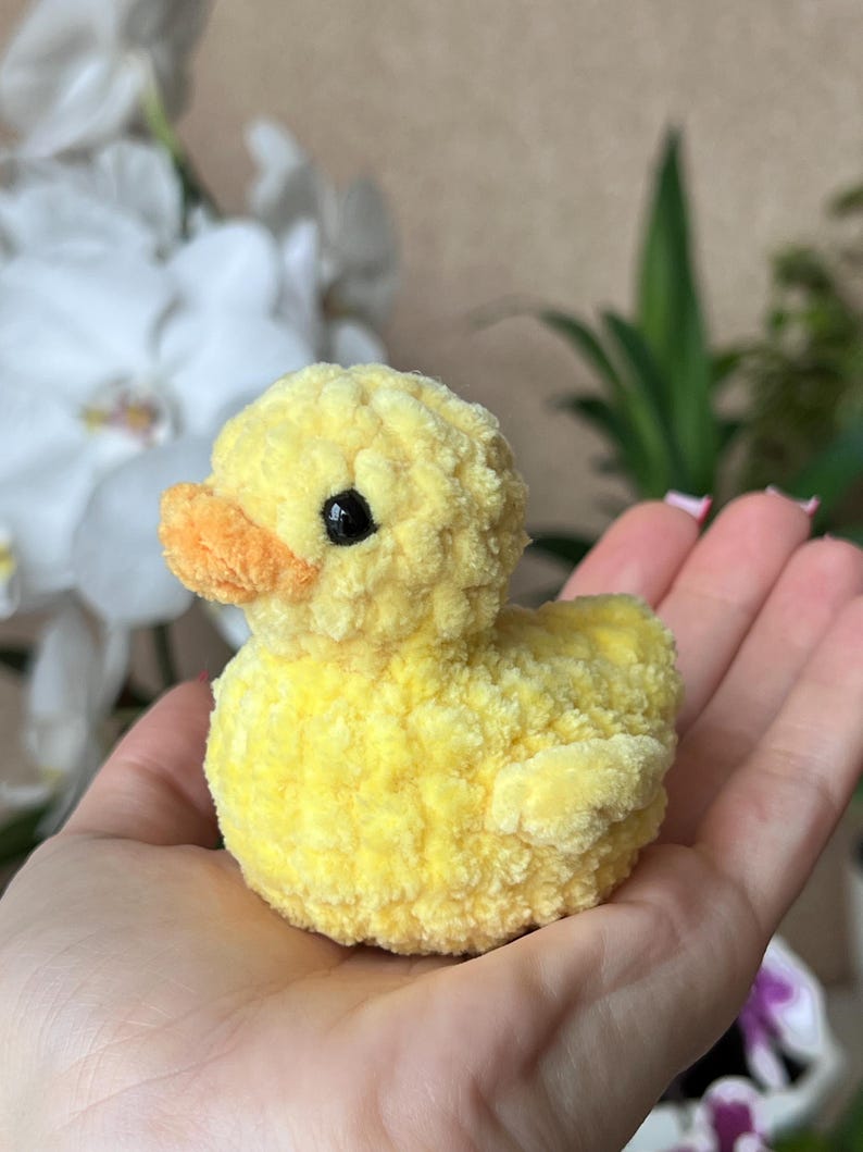Puede incluir: Un peque&ntilde;o patito amarillo hecho a mano, con pico naranja y ojos negros. El peluche est&aacute; hecho de un material suave y texturizado. El pato es un art&iacute;culo encantador y artesanal.