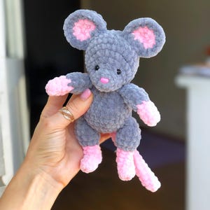 May include: A handmade gray plush mouse with large pink-lined ears, pink paws, and a pink nose. The stuffed animal is soft and cuddly, perfect for a child's toy or nursery decor.