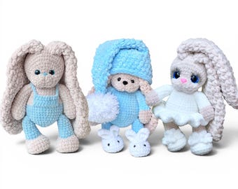 May include: Three crocheted plush rabbit dolls with long ears. The left rabbit wears blue overalls. The center rabbit wears a blue outfit with a matching nightcap and white slippers. The right rabbit wears a white dress with a ruffled skirt.