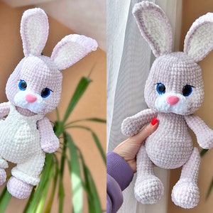 May include: A crocheted plush bunny toy with long ears, a pink nose, and blue eyes. The bunny is wearing a white crocheted outfit with straps.