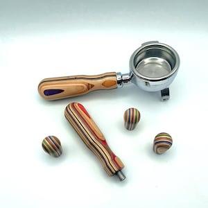 Könnte beinhalten: Ein verchromter Espressomaschinen-Siebträger mit Holzgriff und einem Satz passender Holzzubehörteile. Der Griff und das Zubehör bestehen aus mehrschichtigem Holz in verschiedenen Farben, darunter Rot, Lila und Grün.