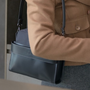 Cartera de mano color grafito, bolso clutch con asas intercambiables; un asa bandolera regulable y un asa corta de cuero.