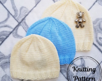 Könnte beinhalten: Drei gestrickte Baby-Mützen in Creme und Hellblau werden gezeigt. Eine silberne Teddybär-Anstecknadel ist an einer cremefarbenen Mütze befestigt. Die Mützen sind auf einer gemusterten Oberfläche angeordnet. Das Bild enthält den Text "Knitting Pattern".