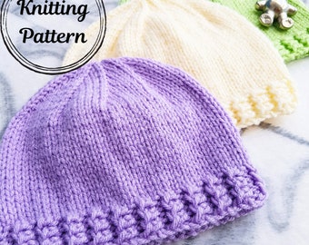 Könnte beinhalten: Drei gestrickte Mützen in verschiedenen Farben: lila, creme und grün. Die Mützen haben alle den gleichen Stil, mit einem einfachen Rippenmuster und einem umgeschlagenen Rand.