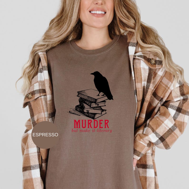 May include: Espresso-colored sweatshirt featuring a black raven perched atop a stack of books. The text "MURDER but make it literary" is printed in red below the books. The sweatshirt is a casual style.
