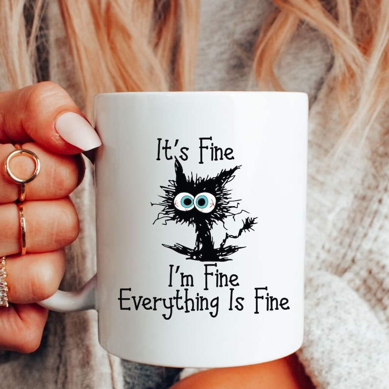 May include: White ceramic mug with a black cat illustration and the text "It's Fine I'm Fine Everything Is Fine".