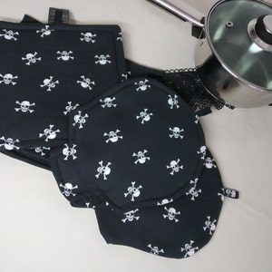 Könnte beinhalten: Satz von vier schwarzen Topflappen mit einem weißen Totenkopf- und Knochenmuster.