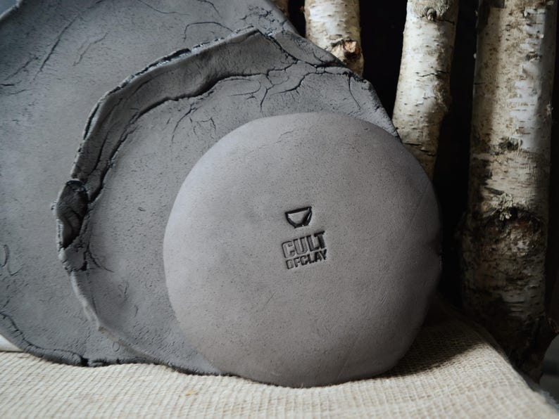 May include: Two gray ceramic plates, one on top of the other, with a smaller gray ceramic bowl on top. The bowl has the text "Cult of Clay" stamped on the bottom.