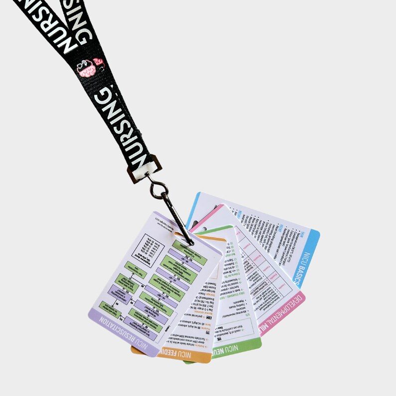 May include: A black lanyard with the word "NURSING" printed on it, attached to a set of colorful laminated cards with titles like "NICU FEEDING", "NICU MEDICATIONS", "DEVELOPMENTAL MILESTONES", "DR. ORDERS", and "NICU BASICS".