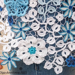 May include: White crochet lace with blue floral details. The lace is delicate and intricate, with a variety of different flower shapes and sizes. The lace is perfect for adding a touch of elegance to any project.