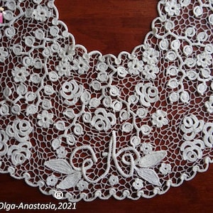 Peut inclure: Collier en dentelle crochet&eacute;e blanche avec un motif floral et un d&eacute;licat motif de roses et de feuilles. Le collier a un bord festonn&eacute; et une petite inscription qui dit "Olga-Anastasia, 2021".