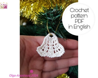 May include: White crocheted bell ornament hanging on a Christmas tree. Crochet pattern PDF in English.