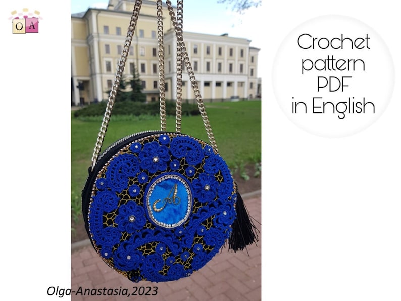 K&ouml;nnte beinhalten: Eine blaue runde H&auml;kel-Tasche mit einer goldenen Kettenkette und einem schwarzen Quasten. Die Tasche hat ein blaues Samtzentrum mit einem goldenen Buchstaben "A" darauf gestickt. Die Tasche befindet sich vor einem Geb&auml;ude mit gr&uuml;nem Gras.