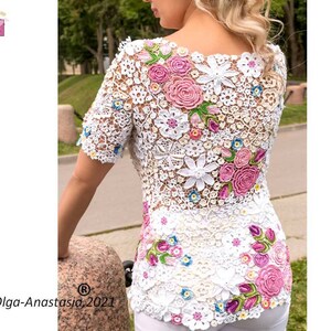 Puede incluir: Top blanco de crochet con un dise&ntilde;o floral con flores rosas, blancas y verdes. El top tiene un escote redondo y mangas cortas.