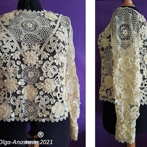 May include: A white crocheted top with a delicate floral design. The top has long sleeves and a round neckline. The top is made with intricate crochet stitches and features a variety of floral motifs.