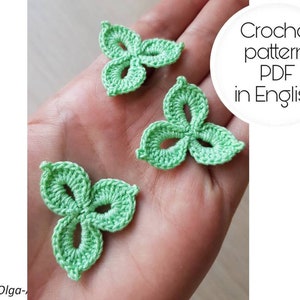 May include: Three crocheted green leaf shapes on a hand. The text "Crochet pattern PDF in English" is in a white circle on the right side of the image.