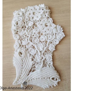 Peut inclure: Dentelle crochet&eacute;e blanche avec un motif floral. La dentelle a un bord festonn&eacute; et un motif d&eacute;licat. La dentelle est sur une surface en bois. Olga-Anastasia, 2022.