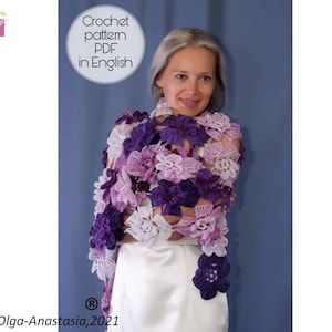 May include: A woman wearing a white top and a purple and white crocheted shawl with a floral design. The shawl is made of multiple shades of purple and white yarn. The text "Crochet pattern PDF in English" is visible in the top left corner of the image. The text "Olga-Anastasia, 2021" is visible in the bottom left corner of the image.