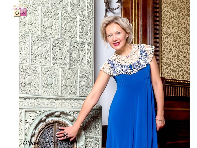 Peut inclure: Une femme portant une robe bleue avec un col en dentelle blanche se tient devant un po&ecirc;le &agrave; carrelage d&eacute;coratif.