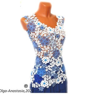 May include: A sleeveless crochet top with a blue and white floral design. The top is made of delicate crocheted flowers in shades of blue and white, with a few small blue beads scattered throughout. The top is fitted and has a V-neckline.