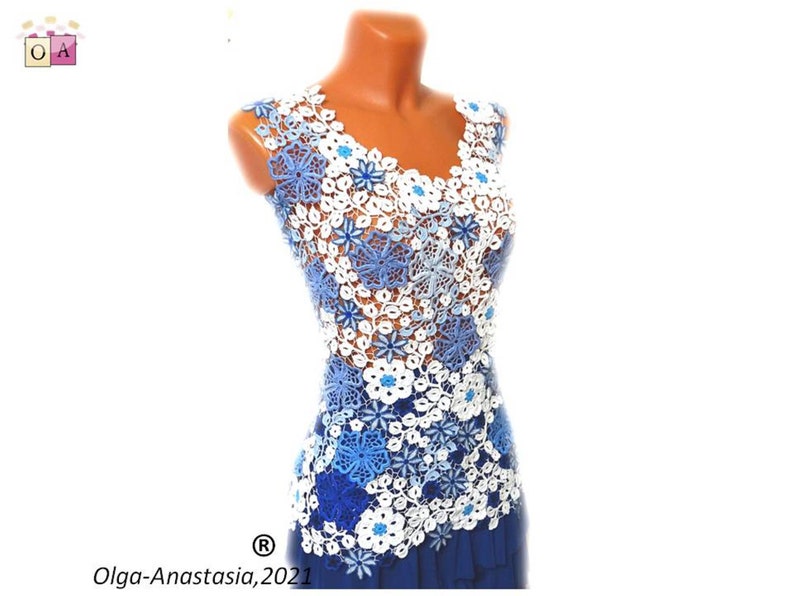 May include: A sleeveless crochet top with a blue and white floral design. The top is made of delicate crocheted flowers in shades of blue and white, with a few small blue beads scattered throughout. The top is fitted and has a V-neckline.