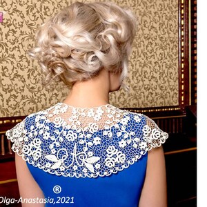 Peut inclure: Un col en dentelle crochet&eacute;e blanche avec un motif floral. Le col est port&eacute; par une personne aux cheveux blonds, mais le visage de la personne n'est pas visible. Le col est sur un fond bleu.