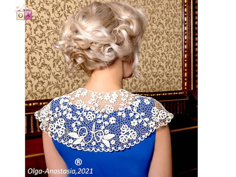 Peut inclure: Un col en dentelle crochet&eacute;e blanche avec un motif floral. Le col est port&eacute; par une personne aux cheveux blonds, mais le visage de la personne n'est pas visible. Le col est sur un fond bleu.