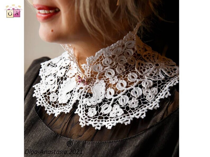 Puede incluir: Un collar de encaje blanco tejido a crochet con un delicado patr&oacute;n floral. El collar se lleva sobre una blusa negra.