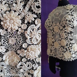 May include: A white crocheted top with a delicate floral pattern. The top features intricate lacework and a variety of flower designs.