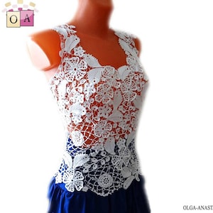May include: White crochet top with a delicate floral pattern. The top is sleeveless and has a scoop neck. It is made of a lightweight, breathable fabric and is perfect for layering.