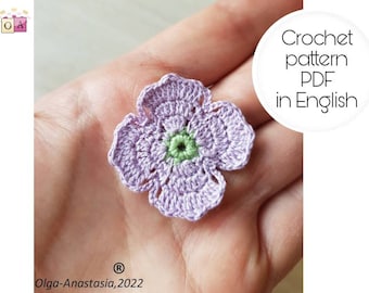 May include: A crochet flower pattern in PDF format, written in English. The flower is a light purple colour with a green centre.