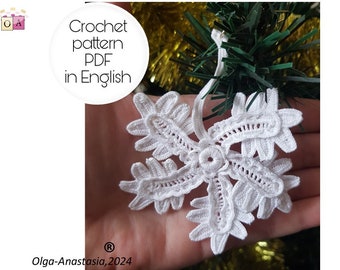 May include: A white, crocheted snowflake ornament with intricate details. The ornament is held against a backdrop of a Christmas tree. Text on the image reads "Crochet pattern PDF in English" and "Olga-Anastasia, 2024".