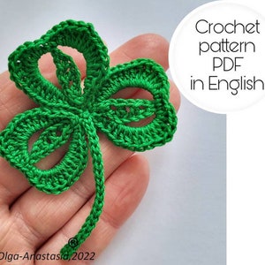 Puede incluir: Un trébol de cuatro hojas tejido a crochet de color verde con un tallo. Patrón de crochet PDF en inglés.