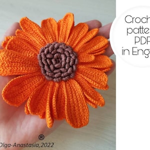 May include: Crochet pattern PDF in English for a bright orange crocheted daisy flower with a brown center.