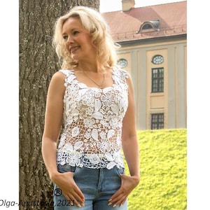 May include: A white crocheted top with a floral design. The top is sleeveless and has a scoop neck. The model is wearing blue jeans.