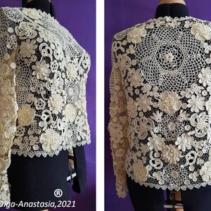 May include: A white crocheted top with long sleeves and a delicate floral design. The top is made with intricate crochet stitches and features a variety of flower shapes.