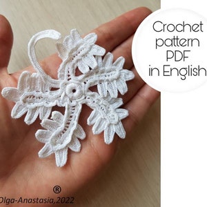 May include: A white crochet flower pattern in PDF format, available in English. The pattern is shown on a hand, with the text "Crochet pattern PDF in English" in a circle around it.