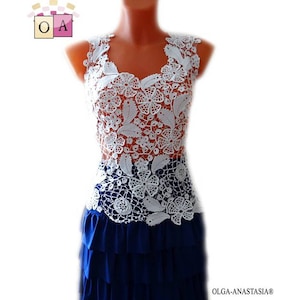 May include: White crochet top with a floral design. The top is sleeveless and has a scoop neck. The top is worn over a blue skirt.