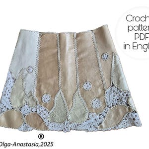 May include: A beige and cream-colored skirt with a unique design. The skirt features panels of varying shades of beige, stitched together. The bottom edge is adorned with a white, crocheted lace trim. The image includes the text "Crochet pattern PDF in English".