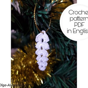 Puede incluir: Adorno de copo de nieve blanco tejido a crochet colgado de un árbol de Navidad. Patrón de crochet PDF en inglés.