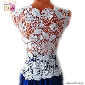 May include: White crochet top with a floral design. The top is sleeveless and has a delicate, intricate pattern.