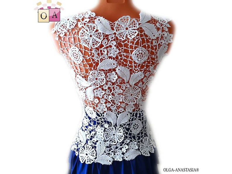 May include: White crochet top with a floral design. The top is sleeveless and has a delicate, intricate pattern.