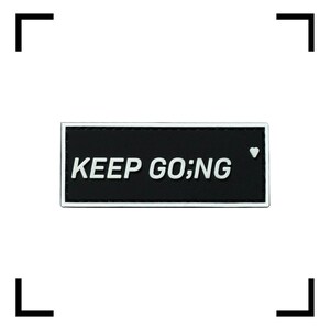 May include: A rectangular black patch with white text that reads "KEEP GO;NG". A small white heart is on the right side of the patch. The patch has a white border.