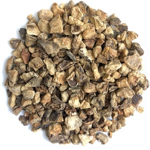 May include: A close-up view of a pile of dried burdock root pieces. The pieces are a light brown color and have a rough, irregular texture.