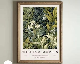 May include: Framed art print featuring a botanical design with lush green foliage and white flowers. The print is labeled "William Morris" with text below that reads "History of British Design" and "The Art of His Century". The frame is a warm, light brown color.