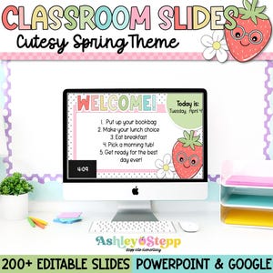 Puede incluir: Una pantalla de ordenador que muestra una diapositiva de bienvenida con un gráfico de fresa y el texto "¡Bienvenido! Hoy es: Martes, 4 de abril". La diapositiva enumera cinco tareas para el día, incluyendo "Pon tu mochila" y "¡Prepárate para el mejor día de todos!" La pantalla está sobre un escritorio con un fondo de patrón rosa y blanco.